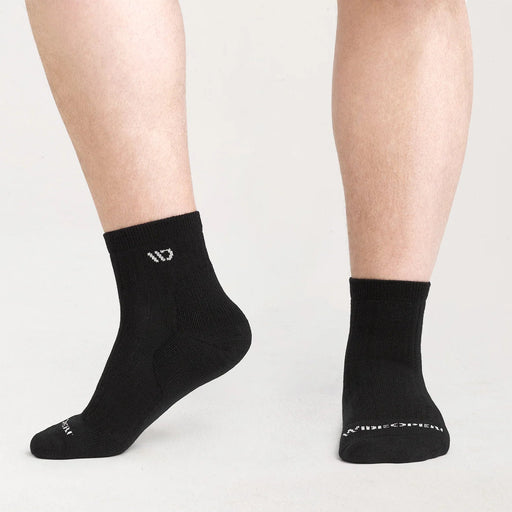 Black socks with a logo worn by a person on a light gray background