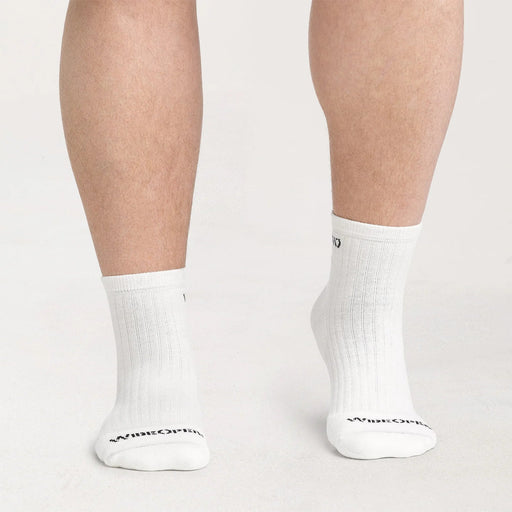 White socks with a brand logo worn by a person on a light gray background