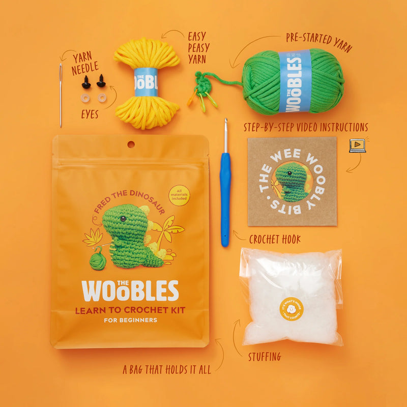 Woobles learn to crochet kit with yarn, hook, and other supplies on an orange background
