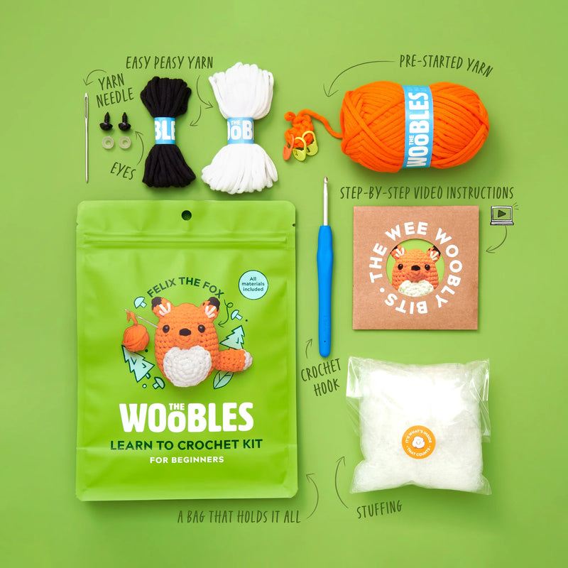 An overview of all the materials included in a Woobles crocheting kit against a green background. 