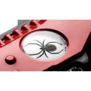 A close-up of a red device featuring a circular clear lens with a black spider graphic printed on it, resembling a spider-eye design.