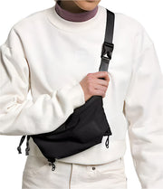 Person wearing a black lumbar bag as a sling bag over one shoulder against a white background