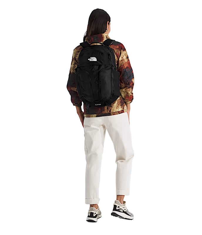 Back view of a woman wearing a black backpack against a white background.