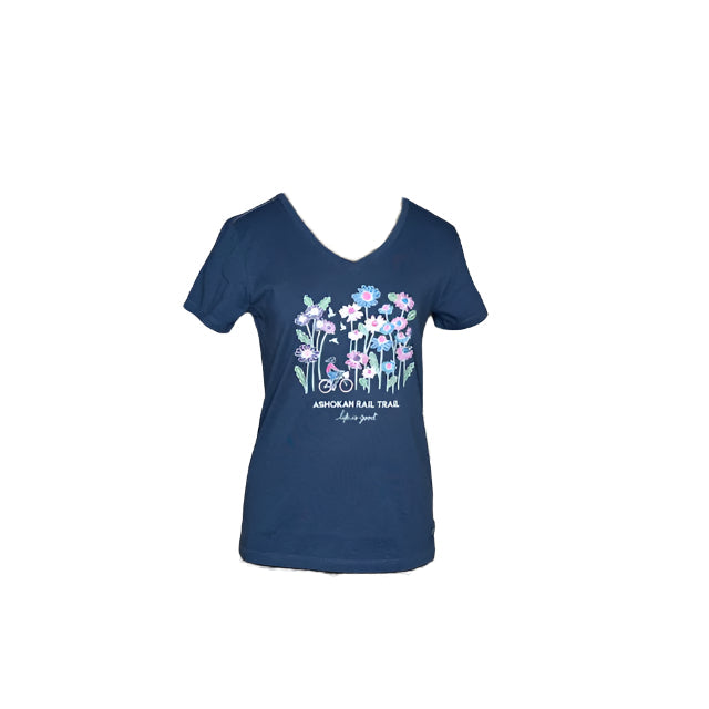 Women's Wildflower Relaxed Short Sleeve V-Neck Ashokan Rail Trail Tee in Darkest Blue. A cycling woman among a forest of larger-than-life wildflowers in pinks, purples, blues, and white is screenprinted on the front.