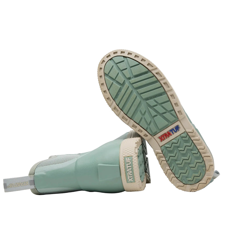 Pair of green rubber boots with beige soles on a white background