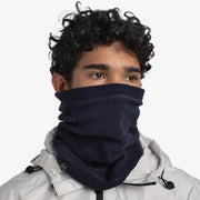 Person wearing a dark blue neck gaiter over a white jacket on a white background