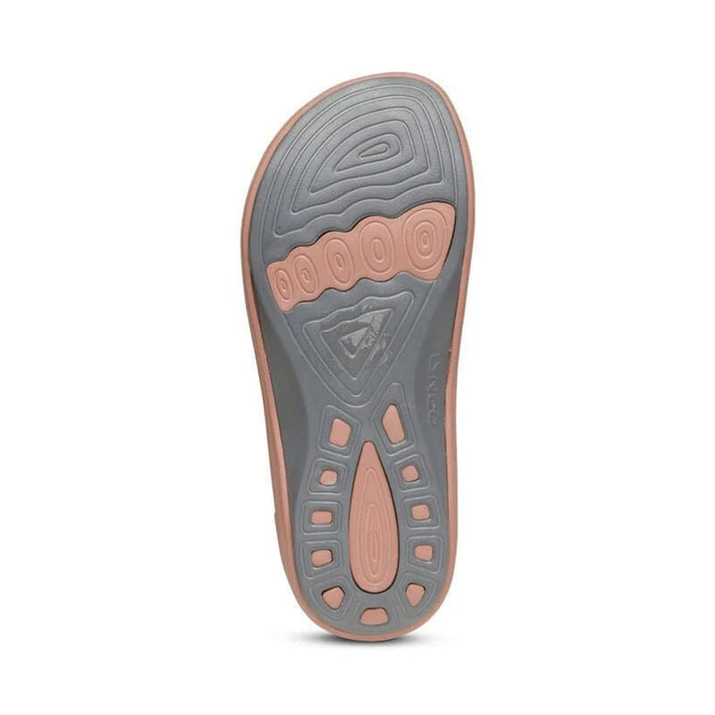 Bottom view of the tread of a grey and pink colored sandal against a white background. 