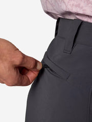 A person wearing dark blue cargo shorts unzipping the back pocket on a white background