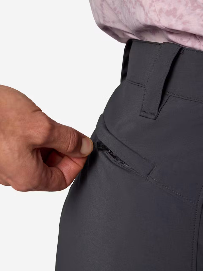 A person wearing dark blue cargo shorts unzipping the back pocket on a white background