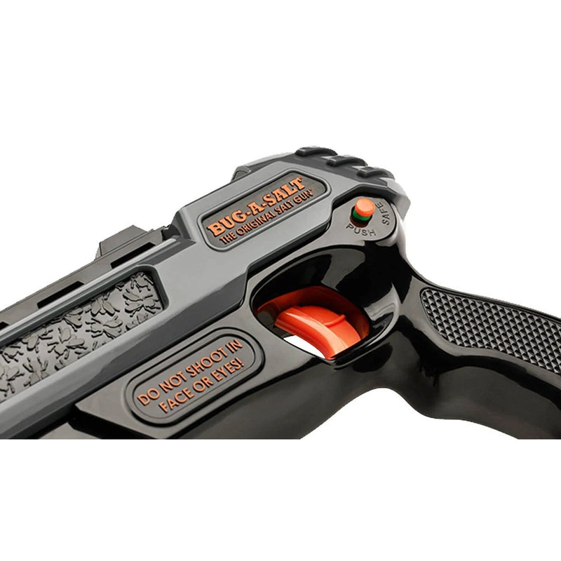 Close-up of a black salt blaster pistol with orange accents, featuring embossed text including 'BUG-A-SALT' and 'DO NOT SHOOT IN FACE OR EYES', on a white background.