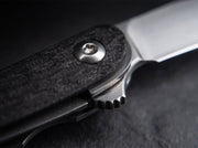Close up image of a black knife handle as well as the closing mechanism on a black background.