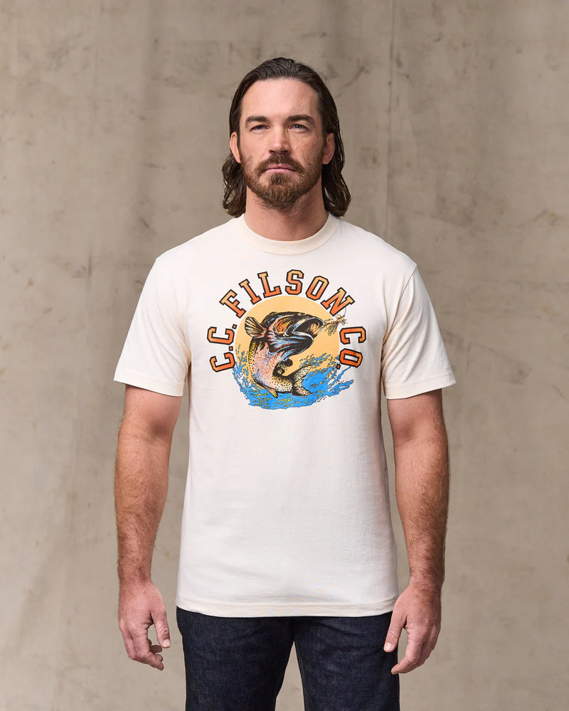 Man wearing a white t-shirt with a graphic design and 'Filson Co' text against a concrete wall.