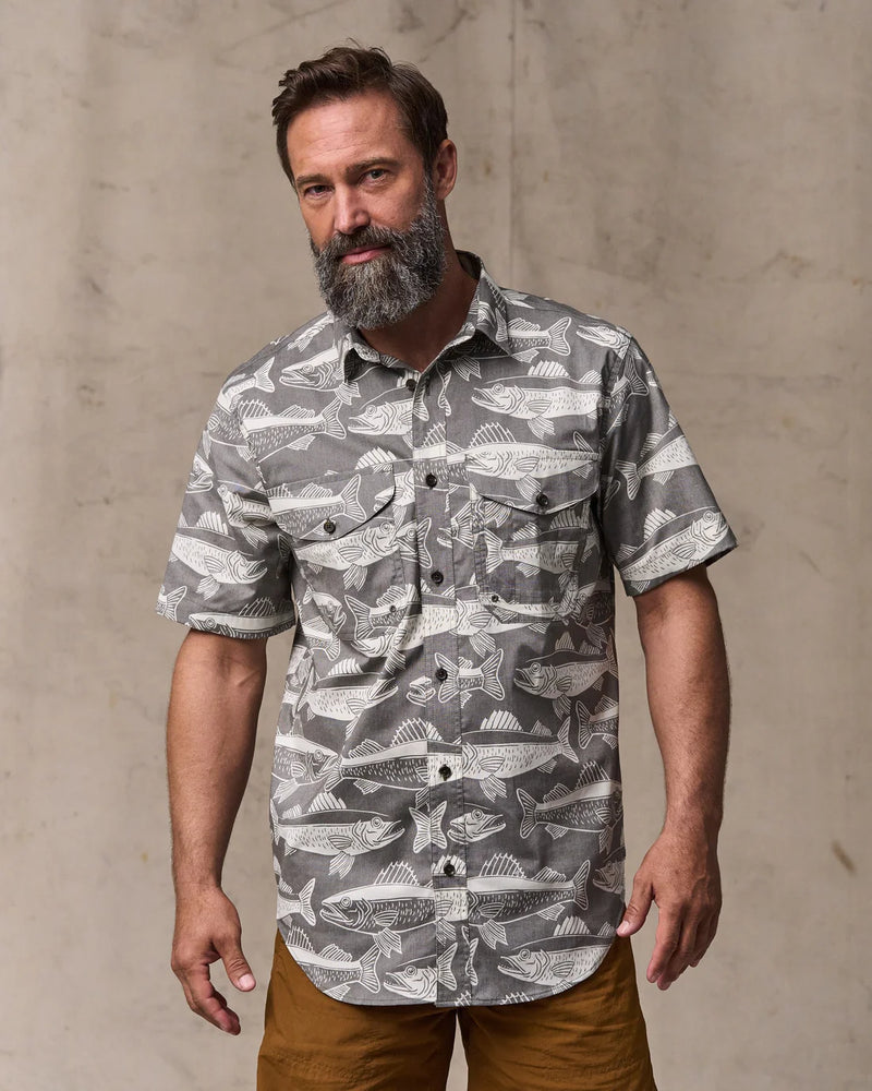 Man wearing a patterned shirt with a neutral background