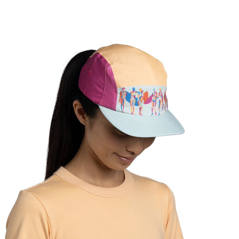 Person wearing a colorful cap with a patterned visor on a white background