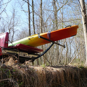 Black boat extender holding up an orange boat over an embankment in a forest.