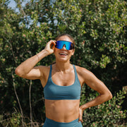 A person wearing a pair of black glasses with blue lenses outside