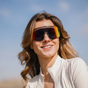 A person wearing a pair of gray glasses with multicolored lenses on a white background