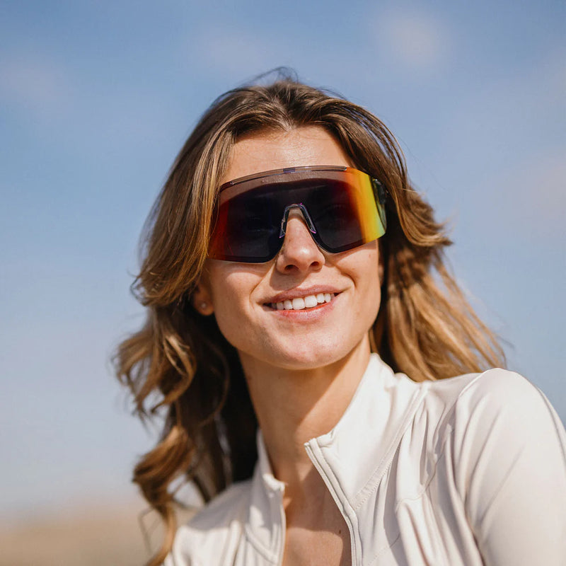 A person wearing a pair of gray glasses with multicolored lenses on a white background
