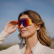 A person wearing a pair of gray glasses with multicolored lenses on a white background