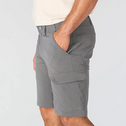 A person wearing gray cargo shorts with hand in their pocket on a white background