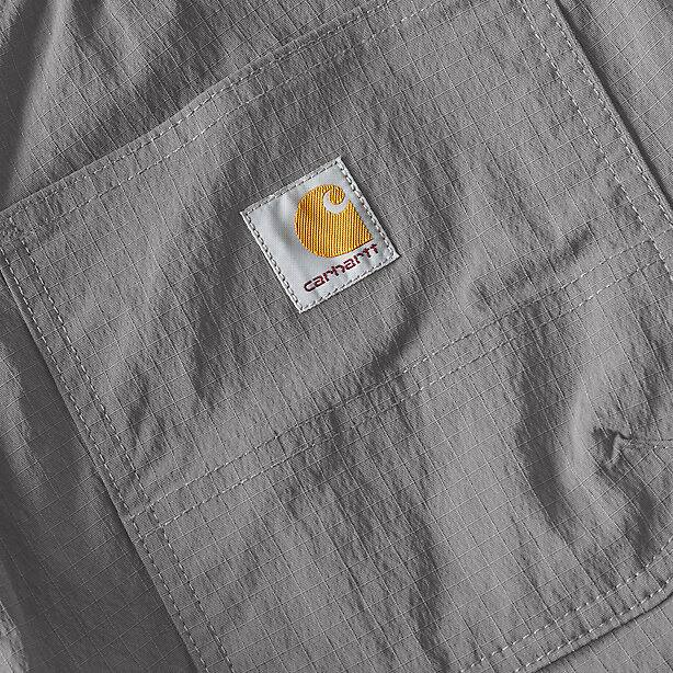 The Carhartt logo on the pocket of gray cargo shorts on a white background
