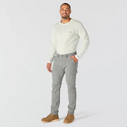 A person wearing gray cargo pants with hand in their pocket on a white background