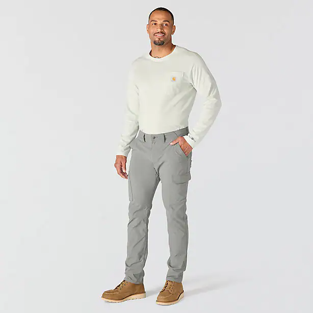A person wearing gray cargo pants with hand in their pocket on a white background
