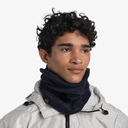 Person wearing a white jacket and navy scarf on a light gray background