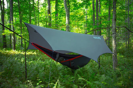 A gray tarp covering a hammock in a forest