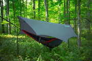 A gray tarp covering a hammock in a forest