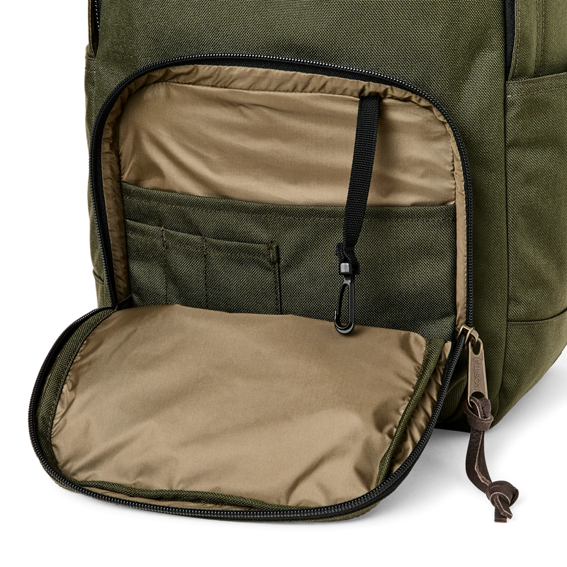 Close up side view of an olive colored backpack with it's side compartment open against a white background. 