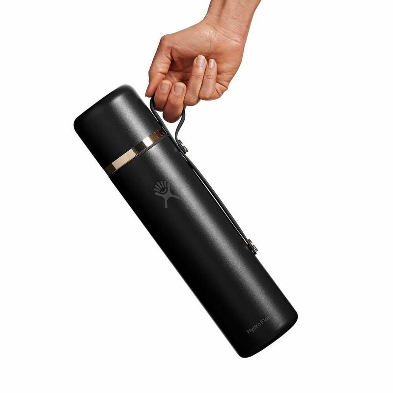 Black thermos held by a hand on a white background
