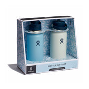 Hydro Flask bottle gift set in retail packaging, featuring two reusable water bottles side by side. The left bottle is matte light blue with a dark navy cap, and the right bottle is matte off-white with a dark navy cap.