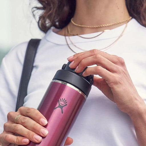 Person holding a maroon water bottle with a black lid, wearing a white shirt.