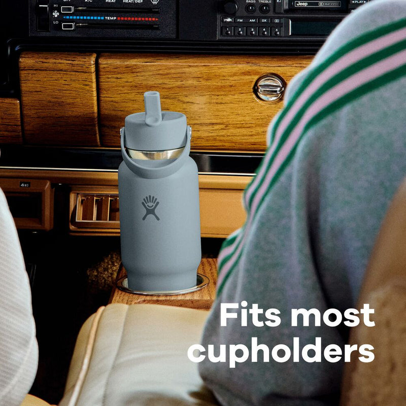 Gray water bottle with a straw lid on a wooden surface inside a vehicle, with text 'Fits most cupholders'.