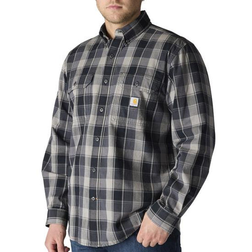 A man wearing a Carhartt long-sleeve plaid button-down shirt in dark gray and beige, paired with blue jeans against a plain white background.