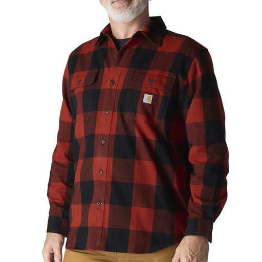 A man wearing a red and black buffalo plaid long-sleeve flannel shirt with a small Carhartt logo patch on the chest pocket, shown against a plain white background.