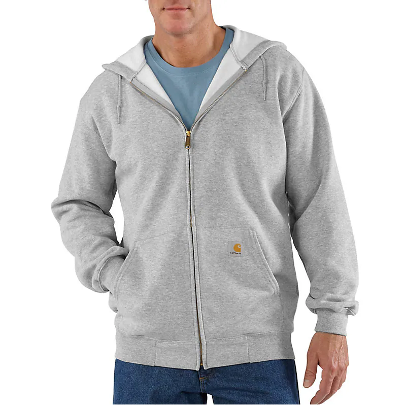 A man wearing a light gray full-zip hoodie with a white hood lining, layered over a blue t-shirt and blue jeans. The Carhartt logo is visible on the chest pocket.