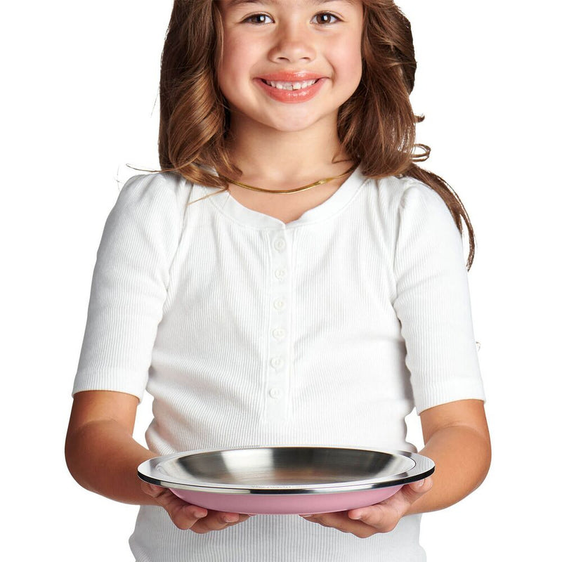 A young girl with brown hair wearing a white short-sleeve henley shirt holds a round metal camping plate with a pink bottom rim against a solid white background.