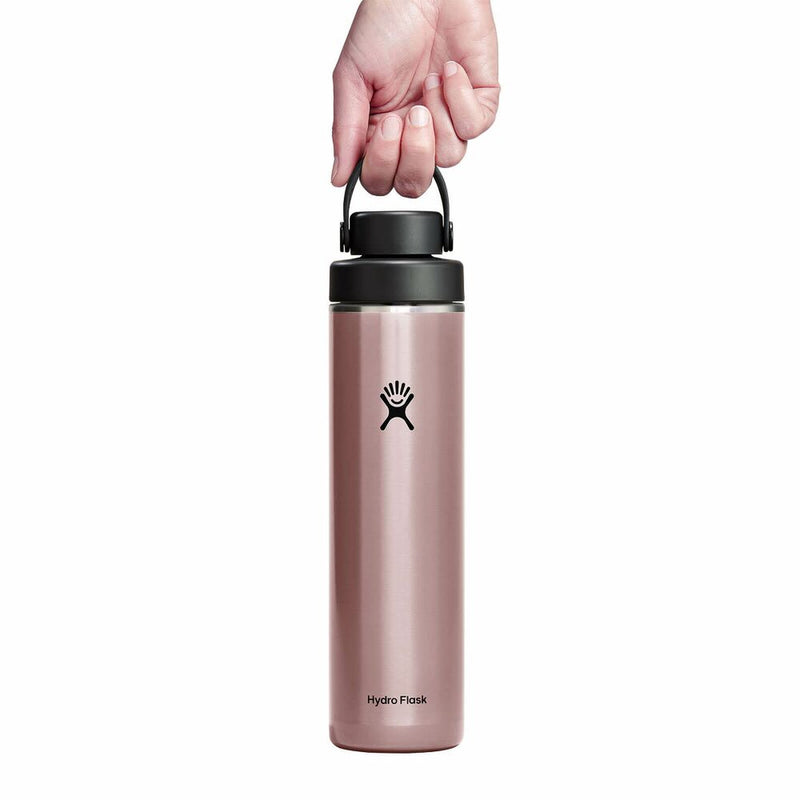 Pink Hydro Flask water bottle with black lid held by a hand on a white background
