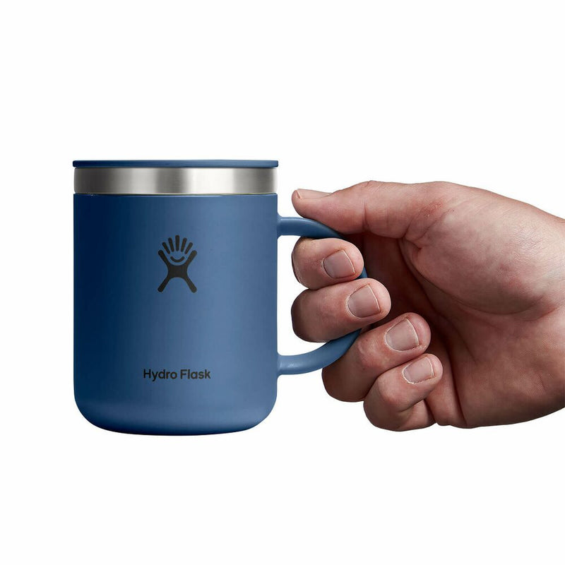 Hand holding a blue Hydro Flask mug on a white background