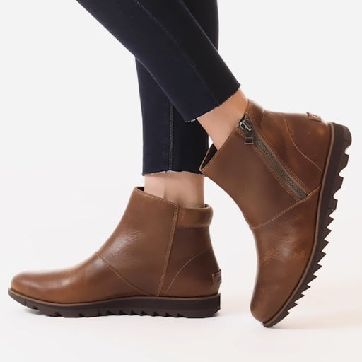 Brown ankle boots worn with dark pants on a white background