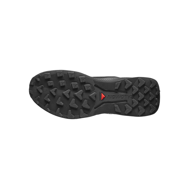 The black rubber outsole of a hiking shoe, featuring deep lugs and a small red triangular logo , shown against a plain white background