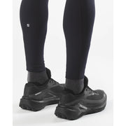 Black hiking shoes with visible brand logo worn with black leggings on a white background