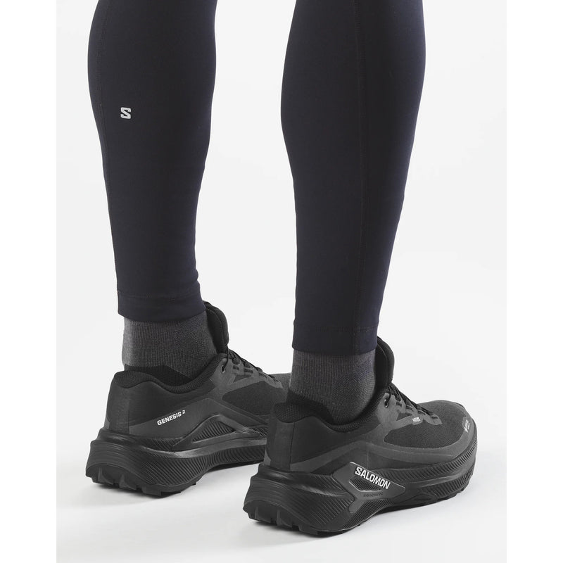 Black hiking shoes with visible brand logo worn with black leggings on a white background