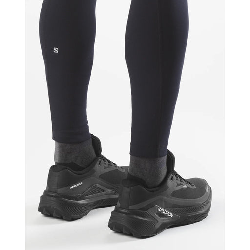 Black hiking shoes with visible brand logo worn with black leggings on a white background