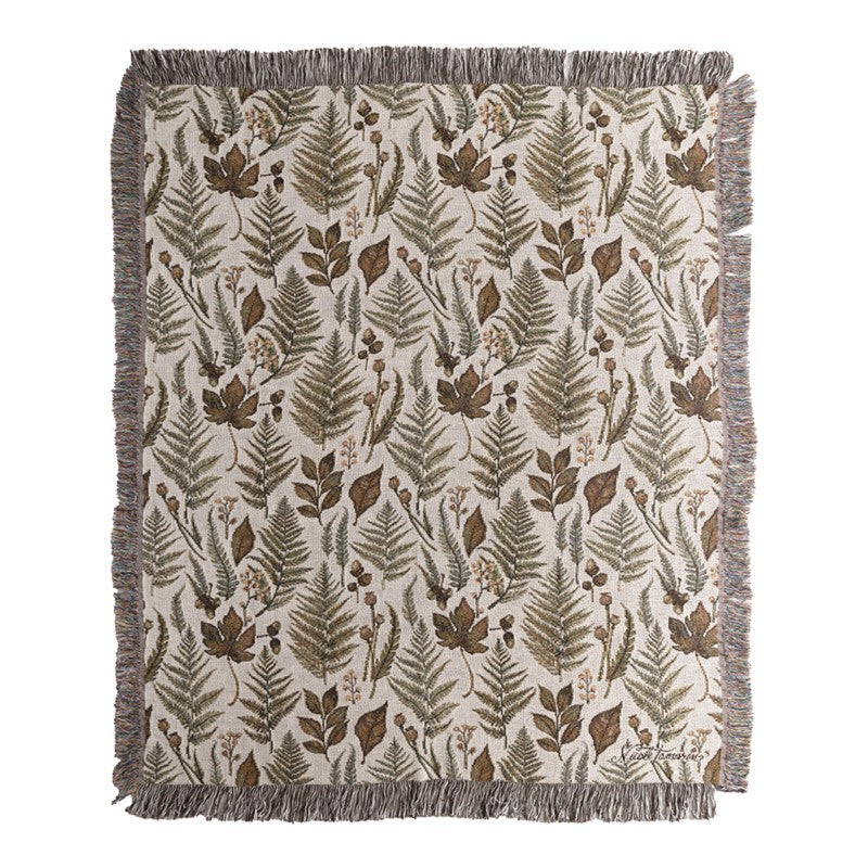 Throw blanket featuring various leaves and plants against a white background. 
