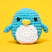 Crocheted penguin toy on a yellow background