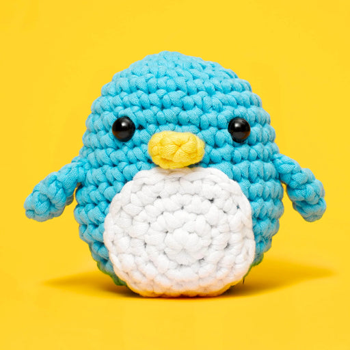 Crocheted penguin toy on a yellow background