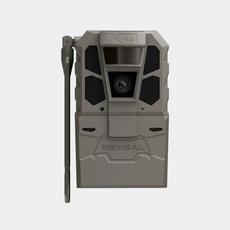 A gray and black trail camera with an attached vertical antenna, shown on a light gray background. The front features a textured gray casing with black accents around the lens and a 'REVEAL' logo embossed near the bottom.